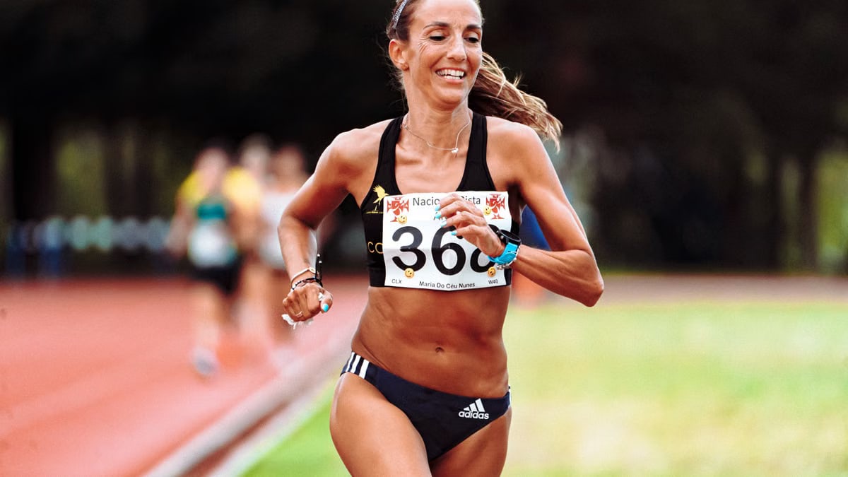 Happy fit ethnic female runner in active wear running on race track during athletic contest in summer